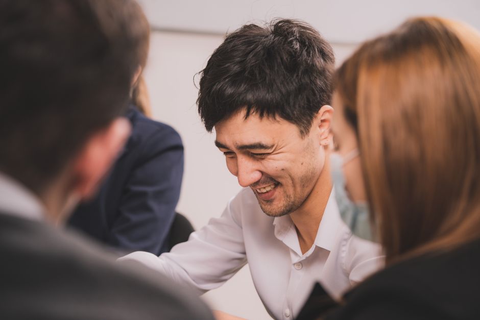 Close-up of smiling colleagues in an indoor meeting, embracing teamwork and collaboration.